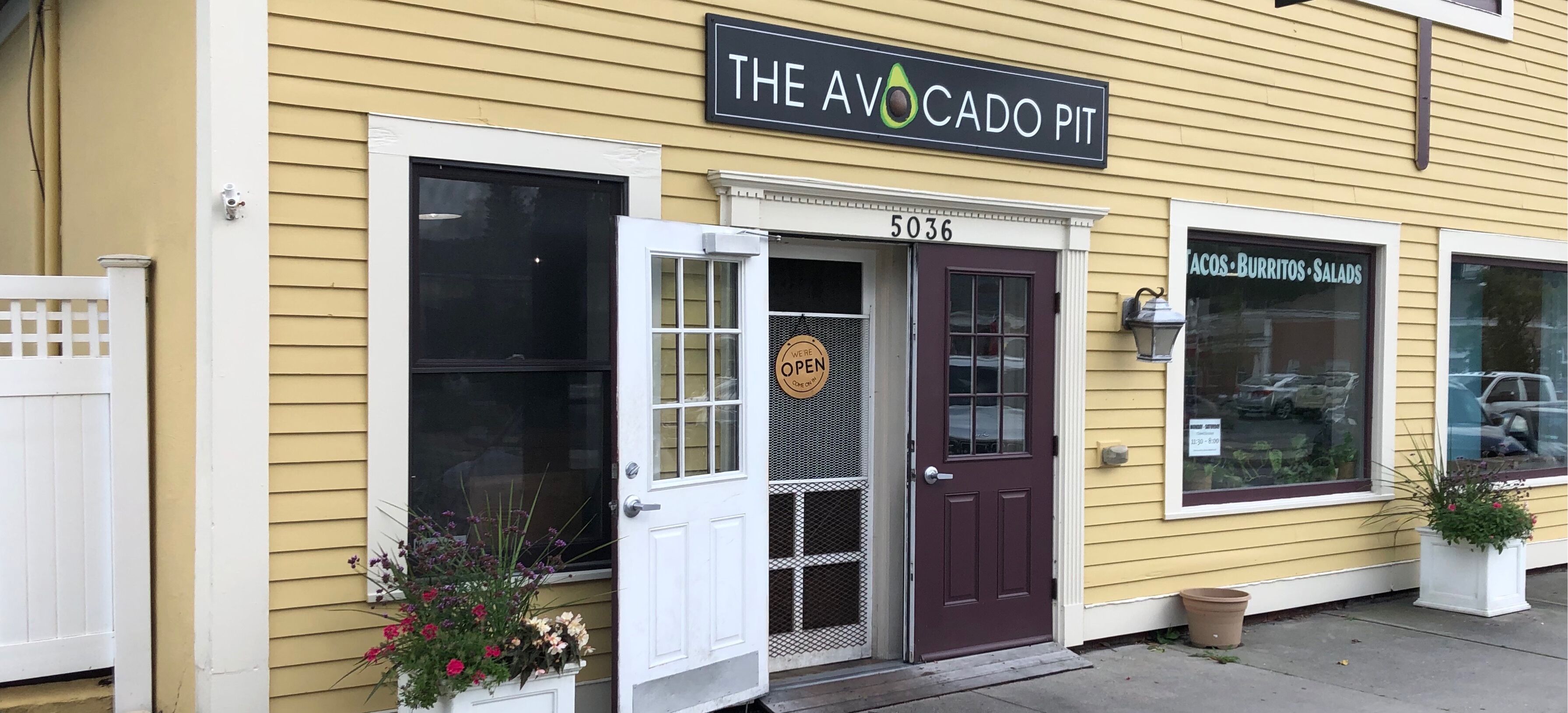 Un bâtiment jaune avec une enseigne indiquant « THE AVOCADO PIT » et un numéro de porte, le 5036.
