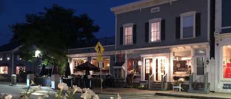 A street view at dusk with a restaurant and a shop with a mannequin in the window.
