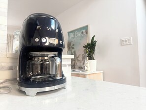 Een zwarte koffiezetapparaat met een helder waterreservoir op een aanrecht.