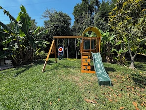 Un parque infantil con columpios, tobogán y zona de escalada.