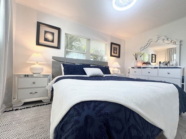 A bedroom with a bed, bedside tables, a dresser, a mirror, and framed pictures on the wall.