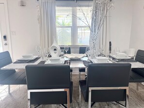A dining area with a table set for four, black chairs, and a vase with branches.