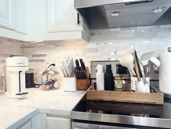 Una cocina con una cafetera Breville, un bloque de cuchillos, una botella de GHEE y una tabla de cortar de madera.