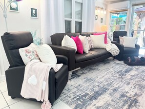 A living room with a black sofa, a black armchair, and a patterned rug.