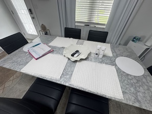 A conference table with white placemats, a white plate with a remote control, and a notebook labeled 'SARASOTA'.