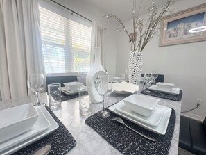 A dining area with a table set for four, including plates, glasses, and cutlery.