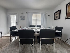 A dining room with a rectangular table, black chairs, a vase, and a framed picture on the wall.