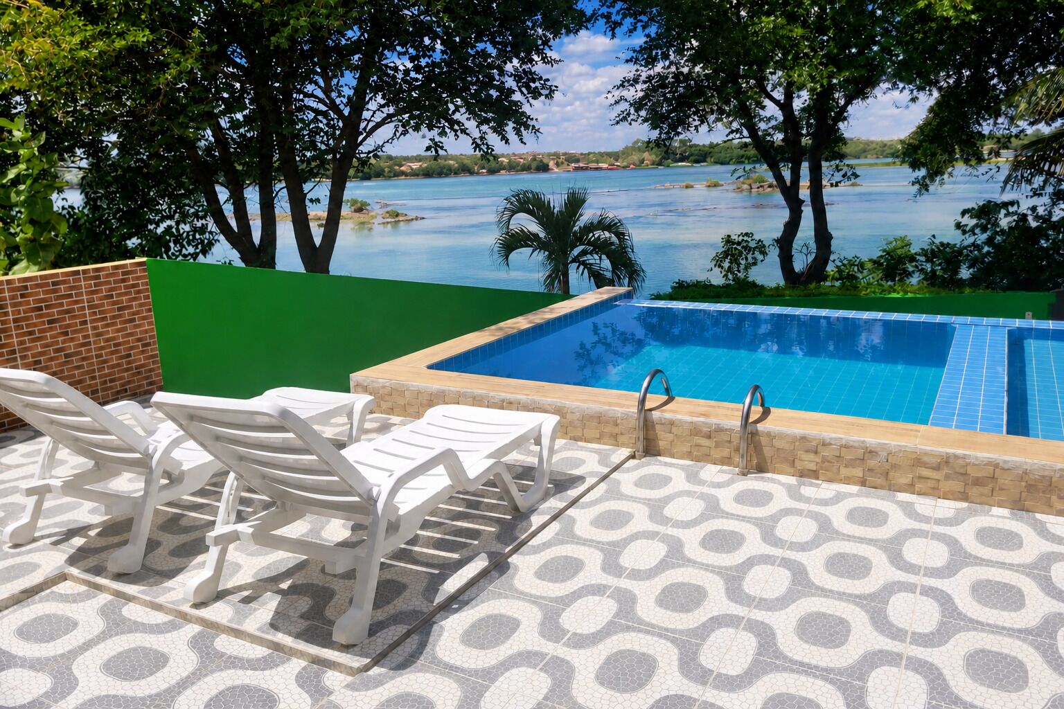 Ein Schwimmbad mit Seeblick, umgeben von Bäumen und einer Terrasse mit Stühlen und Tisch.