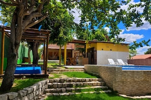 Ein Poolbereich mit einer Steinmauer, einer Hängematte und einer Pergola.
