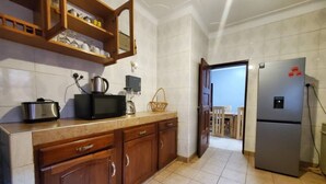 Una cocina con armarios de madera, un microondas, un hervidor y un refrigerador.