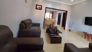 Una sala de estar con un sofá marrón, una mesa de centro con libros y un televisor en la pared.