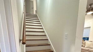 A staircase with wooden steps and white walls. - Hollywood House - Luxurious New Build With 6 Seat Golf Cart! (Bay St. Louis)