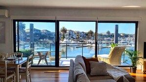 Ein großzügiges Wohnzimmer mit einem großen Schiebeglasfenster mit Blick auf eine Marina.
