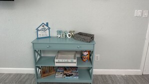 A room with a light blue wall, a shelf with board games, a sign reading "wifi is on the house", and a "welcome" sign above. - Beach Block Apartment w/ Balcony (Clearwater)
