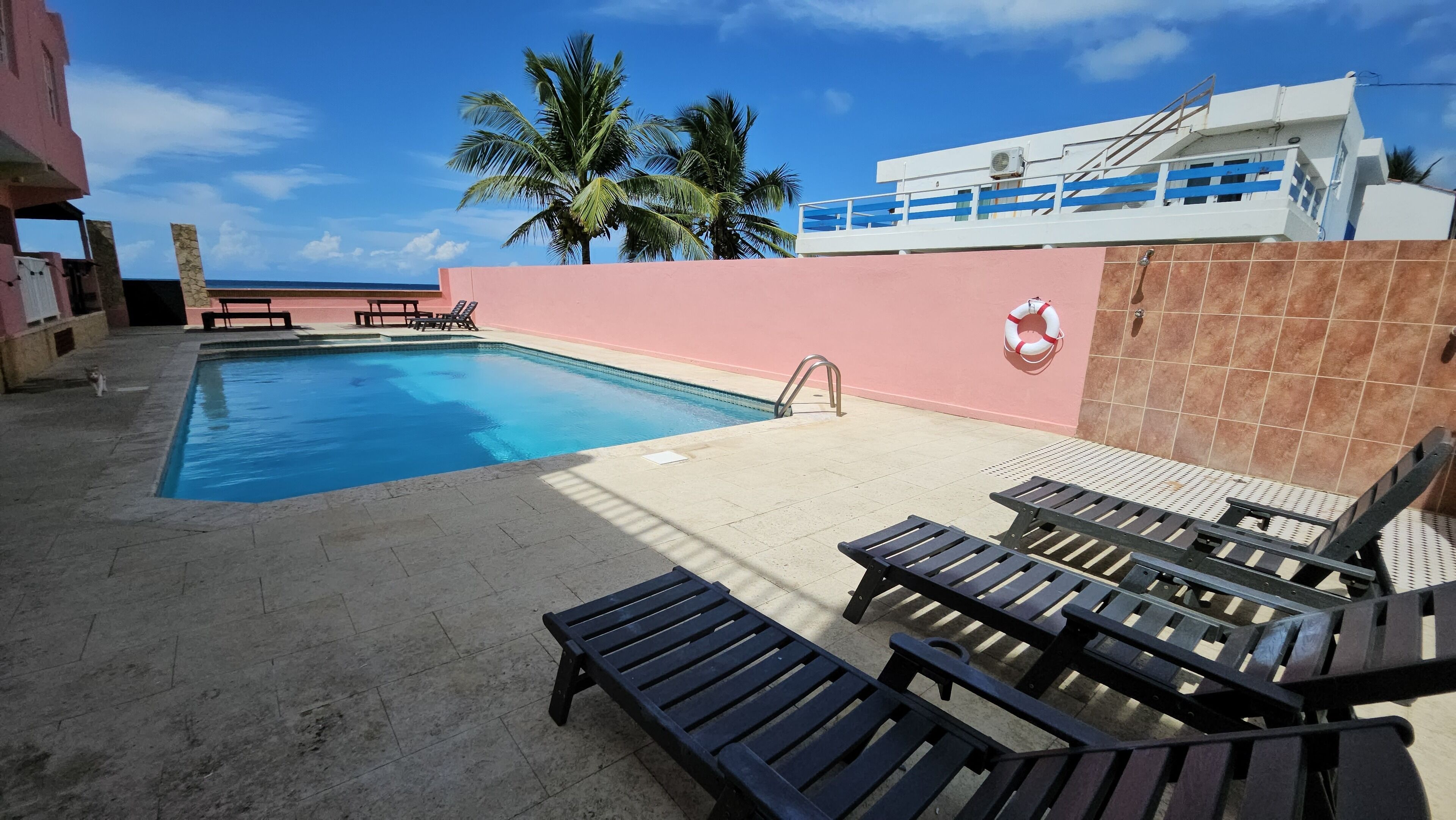Una piscina con lettini, un galleggiante e palme sullo sfondo.