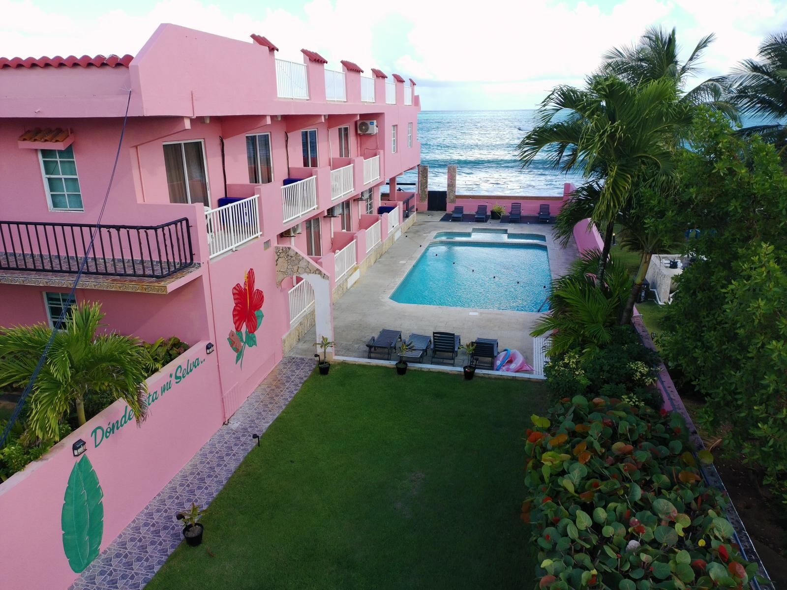 A pink building with a swimming pool and a view of the ocean.