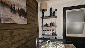 Ein Essbereich mit Holztisch, einer Lampe und einem Regal mit Büchern und Dekoration.