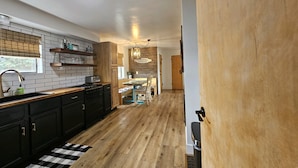 Eine moderne Küche mit schwarzen Schränken, einer Holz Arbeitsplatte und einem schwarz-weißen Schachbrettteppich.