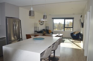 A modern kitchen with a large island, stainless steel appliances, and a dining area with a sofa and chairs.