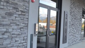 A building entrance with a stone facade, a glass door, and a numbered sign indicating the address. - Mountain View Condo w/ Hot Tube! 2B/1B - Central between Ski Resort and Downown (Revelstoke)