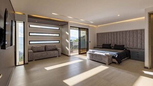 Une chambre moderne avec un grand lit, un canapé et un téléviseur fixé au mur.