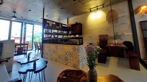 Amplia habitación con techo alto, ventilador de techo y zona de bar con estanterías y objetos decorativos.