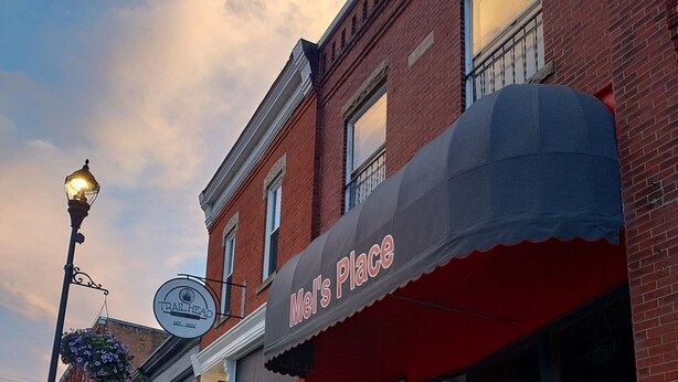 A street view of a building with a red awning and a sign that reads "Mel's Place." - 1800s Victorian Loft  (Concord)
