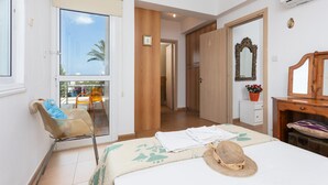 A modern bedroom with a balcony, a wooden wardrobe, a mirror, and a small desk with a chair. - Villa Kalliopi in Pernera (Paralimni)