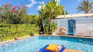 A swimming pool with a blue tiled edge, surrounded by lush greenery and a white fence. - Villa Kalliopi in Pernera (Paralimni)