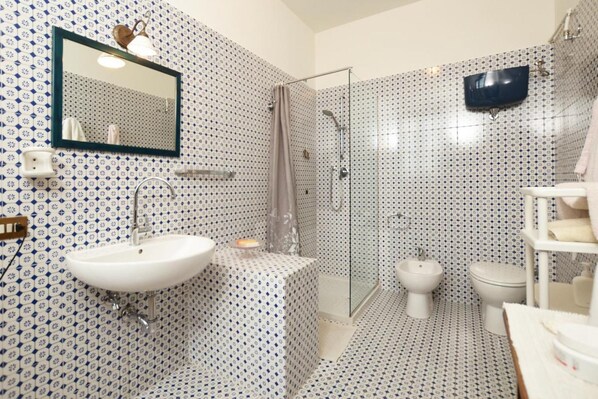 A bathroom with a white sink, a mirror, a shower, and a toilet.