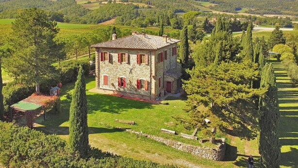 A stone house with red shutters, surrounded by a well-maintained garden and trees, set in a hilly landscape. - Villa Piandisette in Cetona (Cetona)