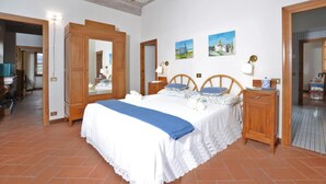 A bedroom with a large bed, wooden headboard, two bedside tables, a mirror, and a view of the outside. - Villa Piandisette in Cetona (Cetona)
