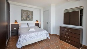 Une chambre à coucher avec un lit, une commode, une armoire et un tableau accroché au mur.