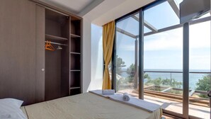 Une chambre avec une grande fenêtre, un lit et une armoire.