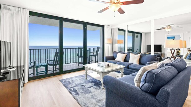 A spacious living area with a balcony overlooking the sea, a ceiling fan, and a modern interior design. - One Seagrove Place 0908 (Santa Rosa Beach)