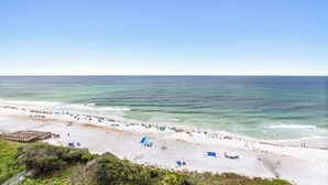 A beach with a wooden pier, sandy shore, and clear blue sky. - One Seagrove Place 0908 (Santa Rosa Beach)