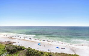 A beach with a wooden pier, sandy shore, and clear blue sky. - One Seagrove Place 0908 (Santa Rosa Beach)