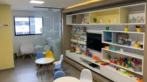 Ein Spielzimmer für Kinder mit Fernseher, Spielzeug und einem weißen Stuhl.