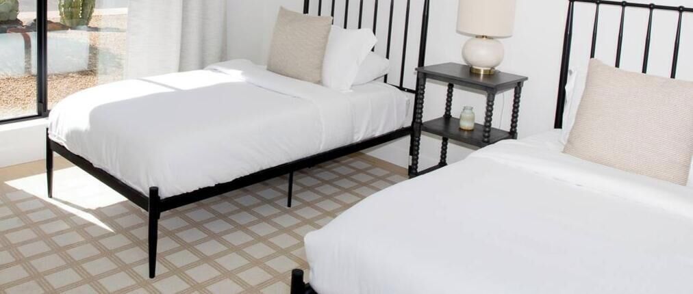 Bright twin bedroom with modern black metal beds and natural light from a large window