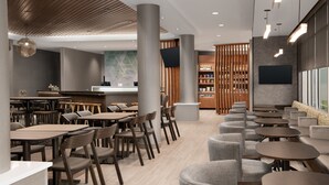 Een modern restaurant met houten tafels en stoelen, een bar en een zithoek met banken en ronde tafels.