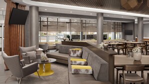 Een moderne lobby met een zithoek, een bar en grote ramen.