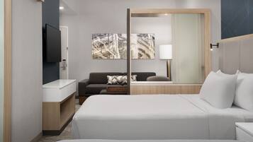 A modern hotel room with a large bed, a sofa, a TV, and artwork on the wall.