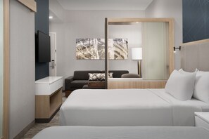 Une chambre d’hôtel moderne avec un grand lit, un canapé, une télévision et des œuvres d’art accrochées au mur.