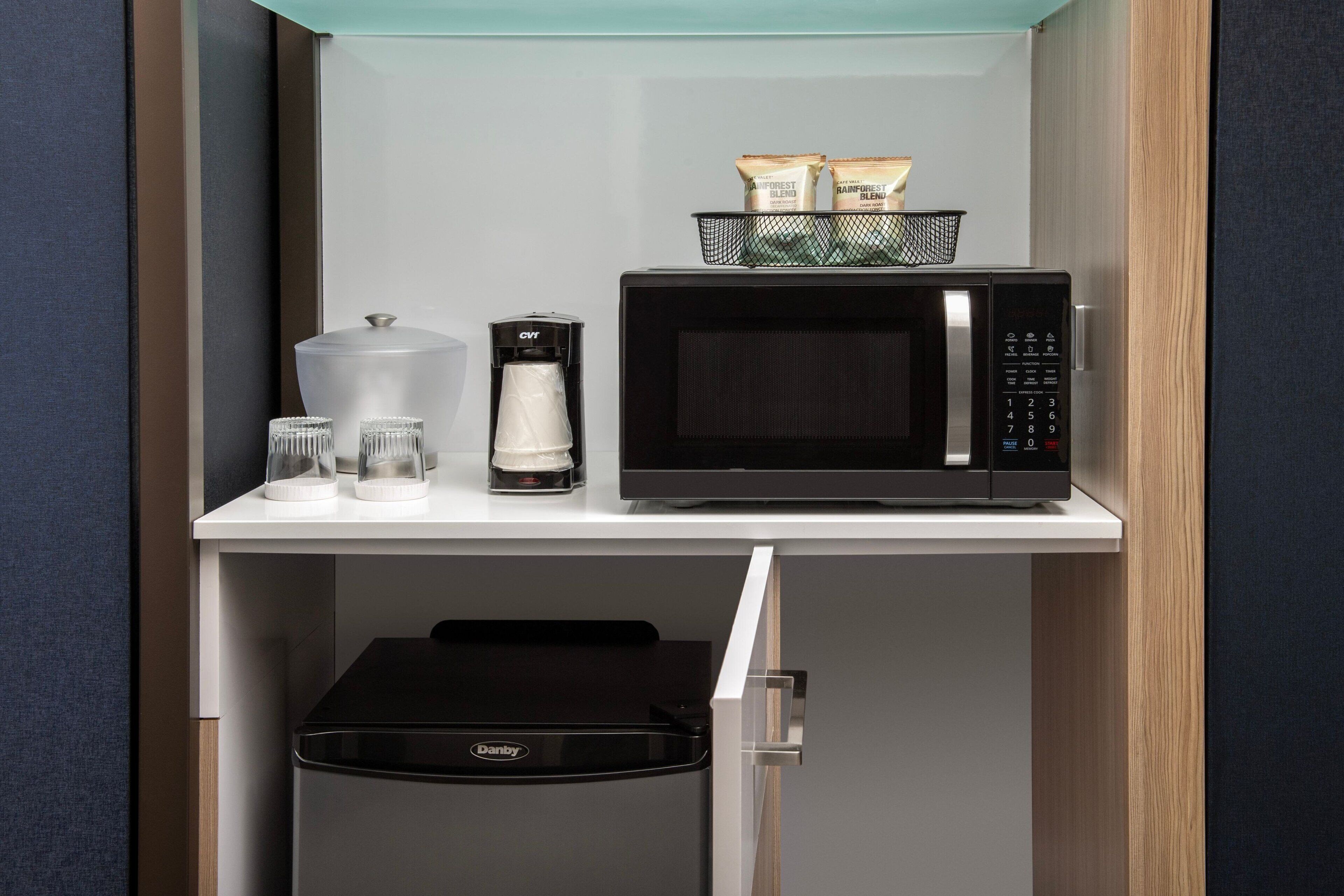 A compact kitchenette with a microwave, coffee maker, and a Danby refrigerator.