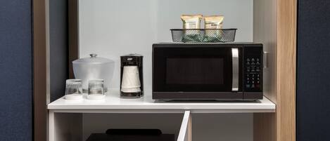 A compact kitchenette with a microwave, coffee maker, and a Danby refrigerator.