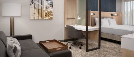Een moderne hotelkamer met een bank, een bureau, een bed en een grote spiegel.
