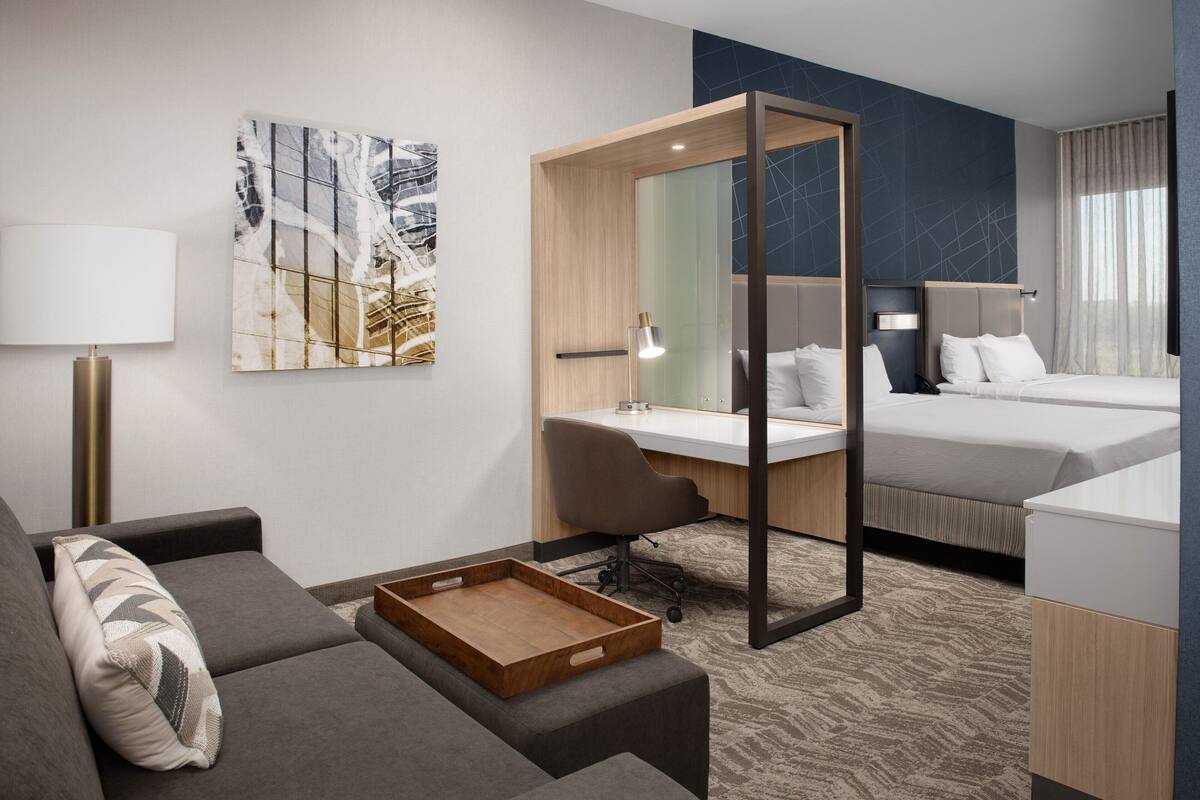 Een moderne hotelkamer met een bank, bureau en bed.