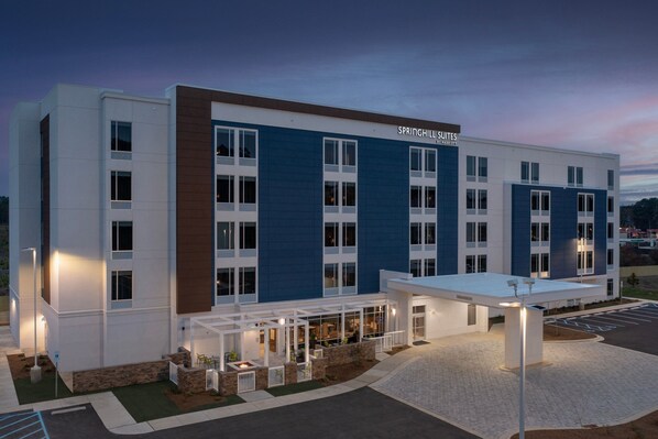 A modern hotel with a blue and white facade, multiple windows, and a covered outdoor area with seating. - Springhill Suites By Marriott Fayetteville I 95 (Fayetteville)