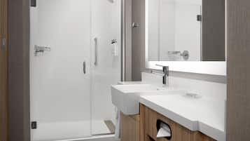 A modern bathroom with a glass shower enclosure, a white sink, and a large mirror.