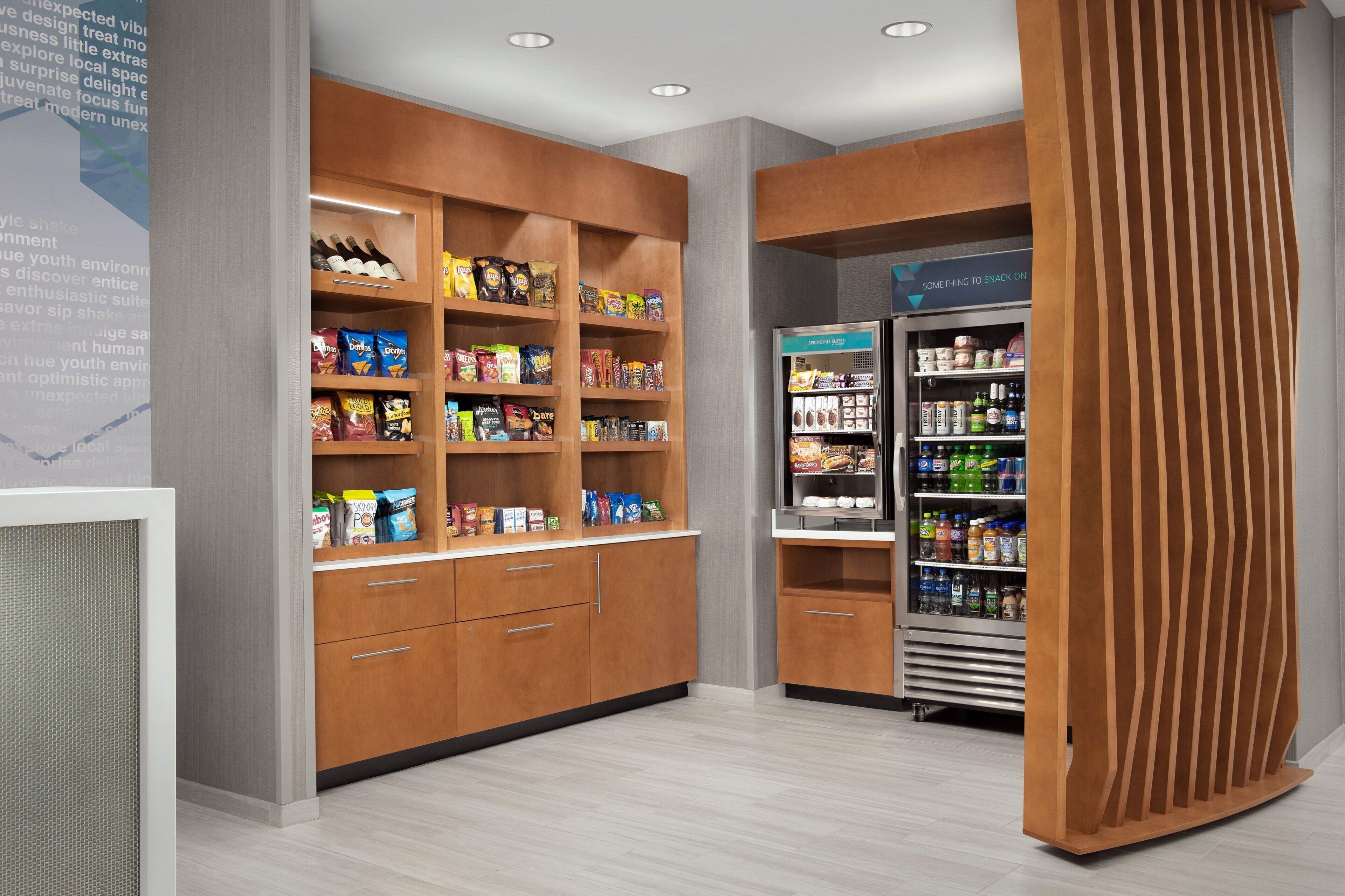 Een snackbar met rekken vol diverse snacks en een koelgedeelte met drankjes.
